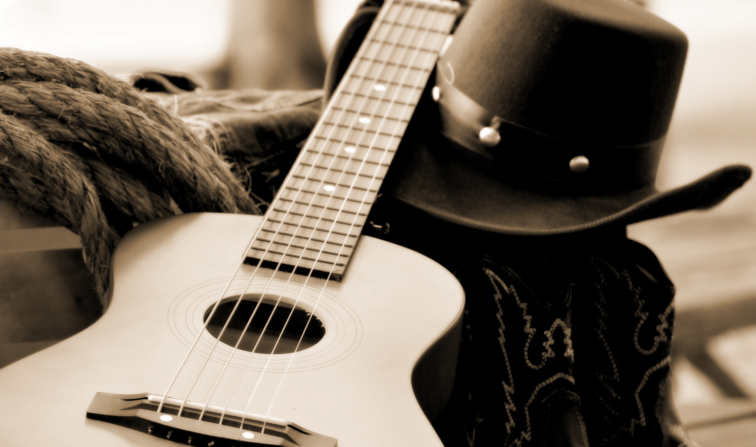 An acoustic guitar, cowboy hat and boots